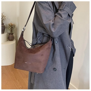 Detail of soft dark brown suede hobo bag with adjustable strap and fashion lettering