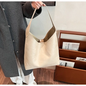 Side view of an elegant beige large capacity soft PU leather tote bag worn on shoulder