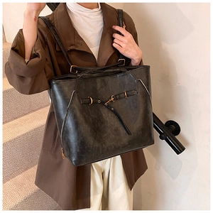Detail of vintage black oil-wax leather tote with golden hardware and side zipper accents