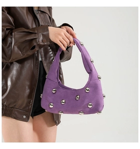 Detail of purple suede crescent handbag with silver sphere studs held by model