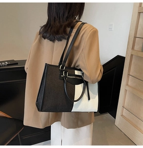 Rear view of a model carrying a black and white color-block tote bag in felt and leather