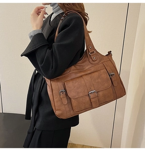 Brown vintage textured leather tote bag showing large capacity and buckle detail on model