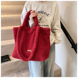 Detail of red fuzzy tote bag with textured lamb wool fabric and leather logo tag