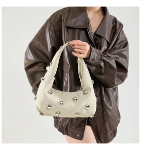 Detail of off-white underarm bag with silver spherical rivets and matte texture