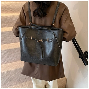 Detail of vintage oil-wax leather tote showing metallic buckles and dual strap design
