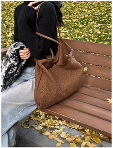 Detail of soft brown textured tote bag with leather straps in an autumn outdoor setting