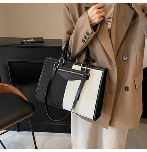 Detail of a large color-block tote bag with textured tweed fabric and silver zipper accents