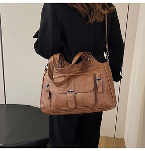 Detail view of a vintage brown leather tote bag showing front flap pocket and adjustable strap