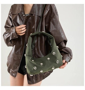 Detail of dark green suede bag with silver studs worn with a brown leather jacket