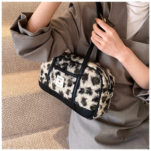 Close-up of leopard print plush bag with black leather straps and brand label detail
