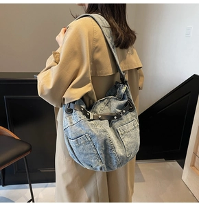 Detail of light blue denim tote bag featuring multiple pockets and black leather strap