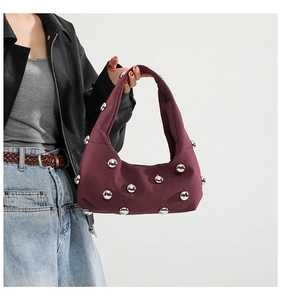 Detail view of dark red canvas underarm bag with dense silver metallic stud rivets