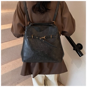 Rear view of a model wearing a black vintage leather backpack with gold hardware buckles