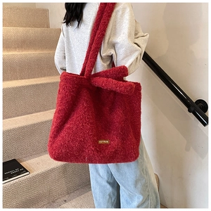 Close-up of red plush tote bag made of lamb wool with leather label detail