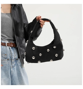Detail of black underarm bag featuring silver metal ball accents and modern texture