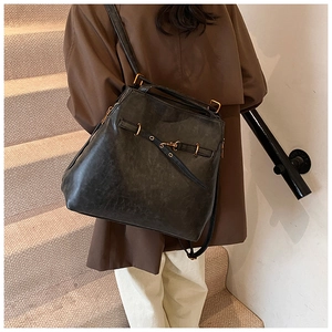 Close-up of black retro leather backpack with golden hardware worn by a model
