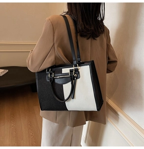 Detail of color-block tote bag with leather straps and silver zipper on model
