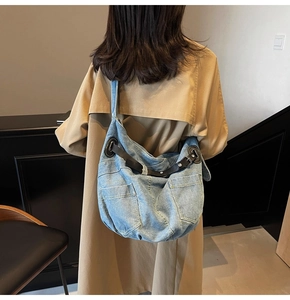 Detail view of large light blue denim tote bag with leather strap adjustment on shoulder