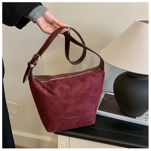 Detail view of burgundy PU leather bucket bag with silver buckles and logo lettering