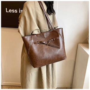 Detail of dark brown oil wax leather tote bag with stylish buckle and zipper accents