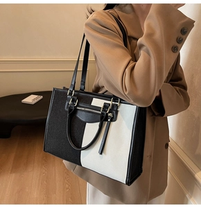 Detail view of large color-block tote bag in black and white with leather zip pocket