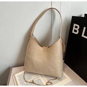 Minimalist beige PU leather hobo bag with gold chain and VEILA logo on a white book