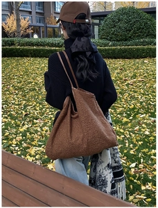 Detail of dark brown faux shearling tote bag with leather handles in autumn setting
