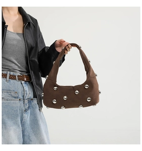 Detail of brown suede shoulder bag with large silver metal studs shown on model