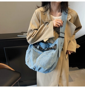 Detail of light blue denim hobo bag with leather straps on a beige coat outfit
