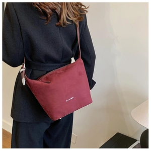 Detail view of burgundy faux suede shoulder bag with white text and metal hardware