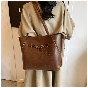 Detail of vintage brown oil wax leather tote bag featuring buckle straps and side zippers