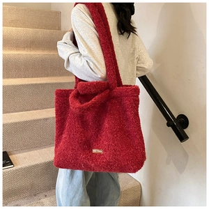 Macro detail of red faux shearling tote bag featuring a leather brand tag and soft texture