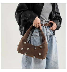 Fashionable dark brown suede tote bag with silver rivet studs styled on a female model
