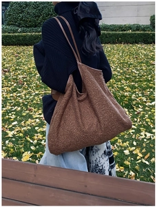 Macro shot of dark brown teddy fur tote bag with leather straps in autumn park