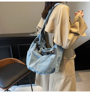 Detail of blue denim shoulder bag with black leather straps and silver metal studs