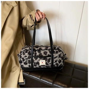 Detail of plush leopard print faux fur cylinder bag with black leather strap and brand label