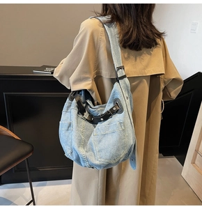 Detail of light blue denim tote bag with cargo pockets and black leather strap worn by a model