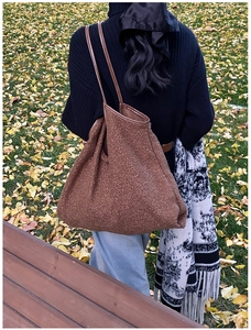 Close-up of brown plush tote bag with sherpa texture and premium leather straps