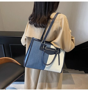 Detail view of contrast color tote bag with dual straps and front zipper pocket on a model