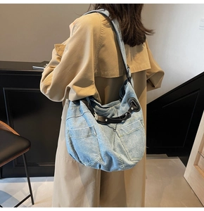 Detailed shot of large denim hobo bag with front pockets and black adjustable leather strap