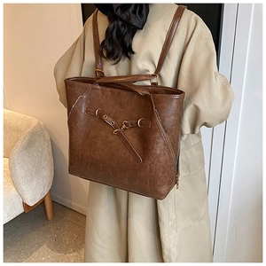 Detail of brown vintage wax leather tote showing versatile straps and metal eyelets