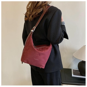 Detail view of burgundy faux suede tote bag with brown adjustable shoulder strap