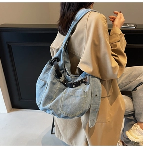Side view of large denim shoulder bag with multi-pockets and leather straps on model