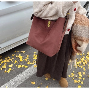 Détail macro du fermoir doré rotatif sur un grand sac cabas en cuir suédé bordeaux