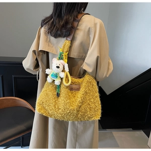 Detail of plush yellow hobo bag with leather strap and cute bear charm on model