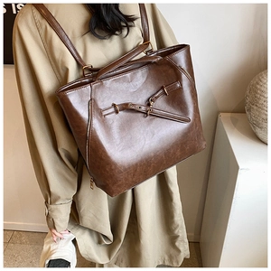 Detail of dark brown vintage faux leather tote showing belt buckle and metal zipper