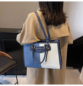 Detail of a large color-block tote bag with dual straps worn by a model in a beige coat
