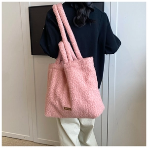 Detail of pink faux shearling tote bag texture and branded leather patch on side