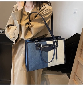 Detailed close-up of a large tote bag featuring blue denim and cream canvas patchwork