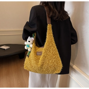 Detail view of yellow plush hobo bag with leather strap and cute bear charm pendant
